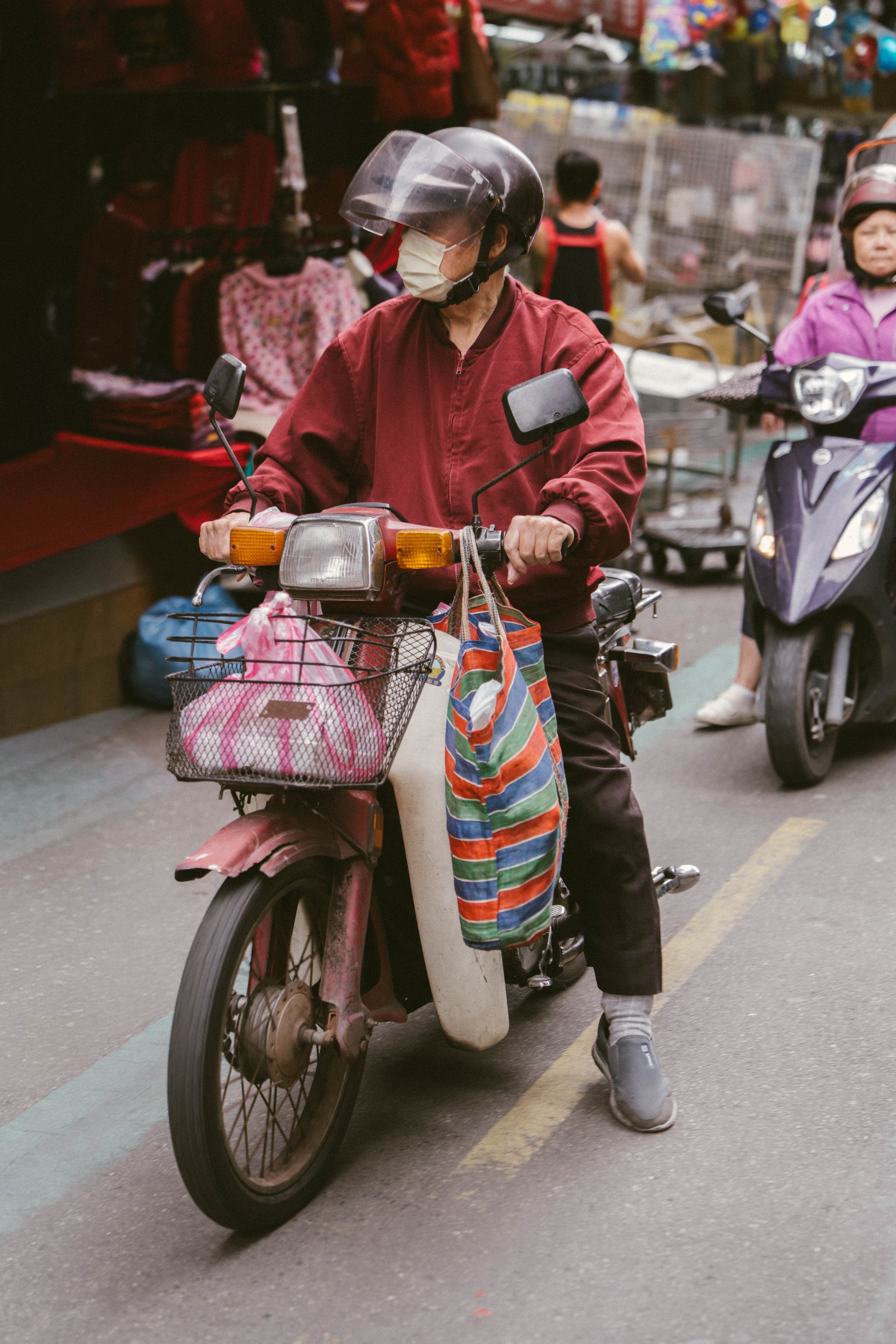 man on motorcycle with produce in bags on handlebars